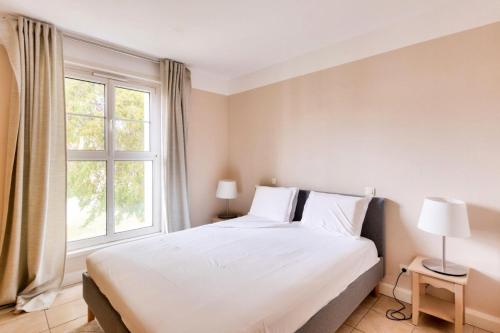 une chambre avec un grand lit blanc et une fenêtre dans l'établissement Résidence Cannes Villa Francia - maeva Home - Appartement climatisé 3 pièces 4 personnes - Sélection MAE-6737, à Cannes