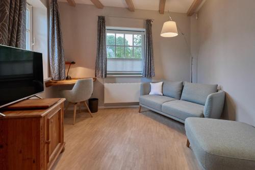 ein Wohnzimmer mit einem Sofa und einem TV in der Unterkunft Hotel Am Steendamm in Oyten