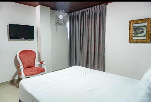 um quarto com uma cama e uma cadeira vermelha em Hotel Suite Santa Rosa em Santa Rosa de Cabal