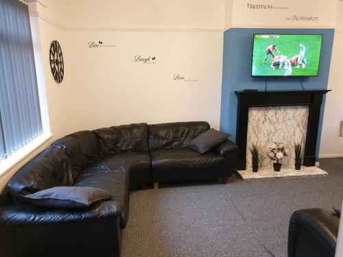 a living room with a leather couch and a tv at Perry House in Nottingham