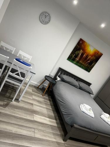1 dormitorio con cama, mesa y reloj en The Cosy Nook en Redruth