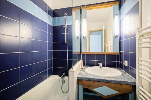 une salle de bain carrelée bleue avec un lavabo et une baignoire dans l'établissement Le Cap Glénan - maeva Home - Appartement 2 Pièces 5 Personnes - Sélection MAE-7427, à Bénodet