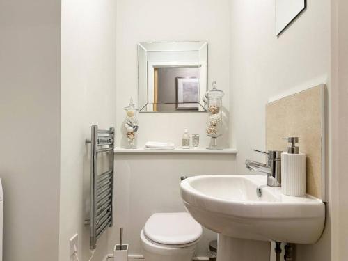 a bathroom with a sink and a toilet and a mirror at Pass the Keys The Coliseum central modern apartment with balcony in Cheltenham