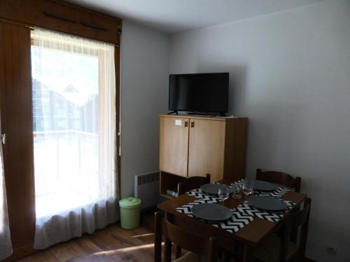 une salle à manger avec une table avec des chaises et une télévision dans l'établissement Résidence L'enclave - Enclave I638 MAE-5354, aux Contamines-Montjoie