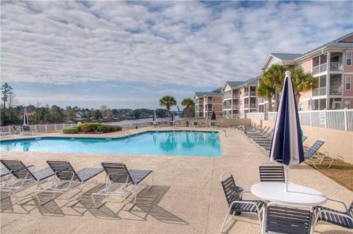 a pool with chairs and a table and an umbrella at Waterway Village by Palmetto Vacations in Myrtle Beach