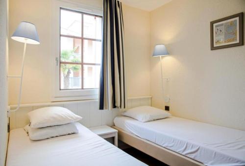 deux lits dans une chambre avec une fenêtre et deux lampes dans l'établissement Résidence Port Bourgenay - maeva Home - Appartement 2 Pièces 5 Personnes - Sélection MAE-9029, à Talmont-Saint-Hilaire