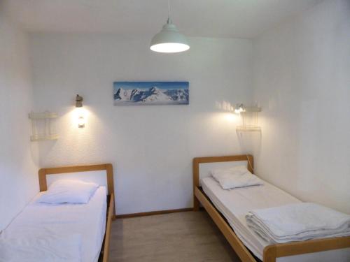 two beds in a room with white walls at Résidence Borgia - 2 Pièces pour 4 Personnes 59 in Les Contamines-Montjoie