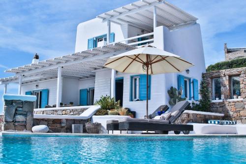 a villa with a swimming pool and an umbrella at Exquisite Mykonos Villa - Villa Lakima - 6 Bedroom - Infinity Pool - Panoramic Sea And Sunset View - Pool Bar in Fanari
