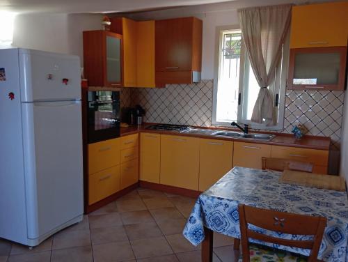 uma cozinha com armários amarelos e um frigorífico branco em La Dimora del Sole em Licata