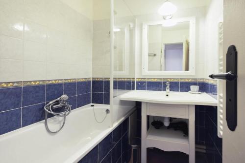 La salle de bains est pourvue d'une baignoire, d'un lavabo et d'un miroir. dans l'établissement Village Pont Royal en Provence - maeva Home - Appartement lumineux 2 Pièces 5 P, à Mallemort