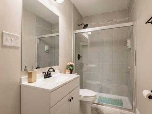 a bathroom with a shower and a toilet and a sink at Spacious 3BR House with Backyard in NULU CozySuites in Louisville
