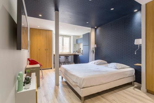 une chambre avec un grand lit avec un mur bleu dans l'établissement Auguste Comte - Studio tout équipé - Cœur de Lyon, à Lyon