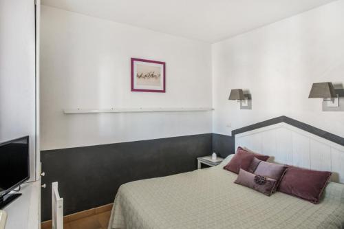Schlafzimmer mit einem Bett mit lila Kissen und einem TV in der Unterkunft Village Pont Royal en Provence - maeva Home - Appartement cosy 2 Pièces 7 Perso in Mallemort