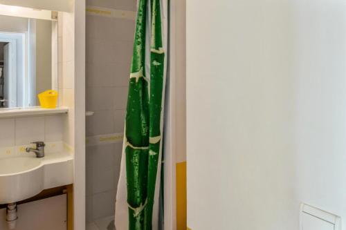La salle de bains est pourvue d'un rideau de douche vert à côté d'un lavabo. dans l'établissement Village Pont Royal en Provence - maeva Home - Appartement cosy 2 pièces 7 personnes vue piscine - Sélection - Super Home MAE-3629, à Mallemort