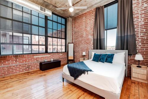 a bedroom with a brick wall and a bed with blue pillows at Stunning 1BR Adler Loft by CozySuites in Saint Louis