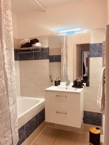 La salle de bains blanche est pourvue d'un lavabo et d'une baignoire. dans l'établissement ELSA / Appartement P3 + Parking, à Nîmes