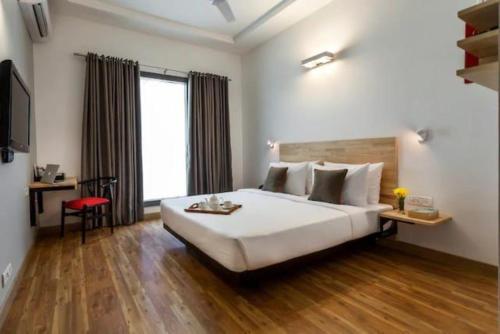 um quarto de hotel com uma cama grande e uma secretária em Hotel JPM Stay - East Of Kailash em Nova Deli