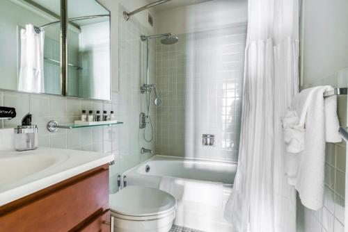 a white bathroom with a tub and a sink at CozySuites 800 Tower 1BR w gym 26 in Louisville