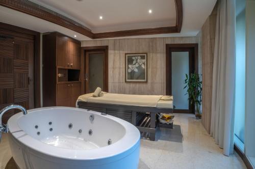 a bathroom with a tub and a bed at The Diplomat Radisson Blu Residence in Manama