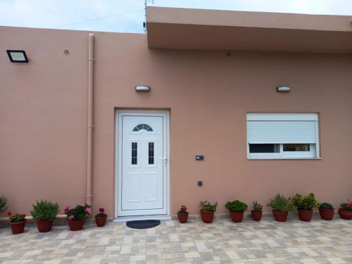 a pink house with a white door and potted plants at KaVros Cozy Apartment in Kavros