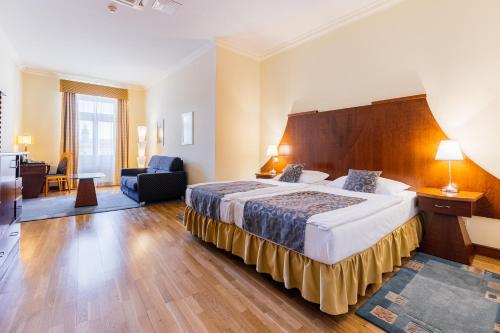 a hotel room with a large bed and a chair at Grandhotel Zvon in České Budějovice