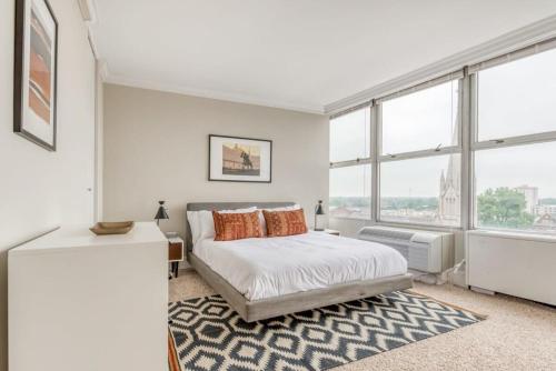 a white bedroom with a bed and large windows at CozySuites 800 Tower 1BR w sky pool, gym! 05 in Louisville