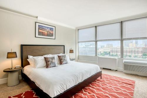 a bedroom with a large bed and large windows at CozySuites 800 Tower 1BR w sky pool, gym! 24 in Louisville