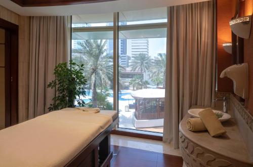 sypialnia z łóżkiem i dużym oknem w obiekcie The Diplomat Radisson Blu Residence w mieście Manama