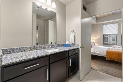 a bathroom with a sink and a mirror and a bed at CozySuites Modern Midtown Condo 04 in Nashville