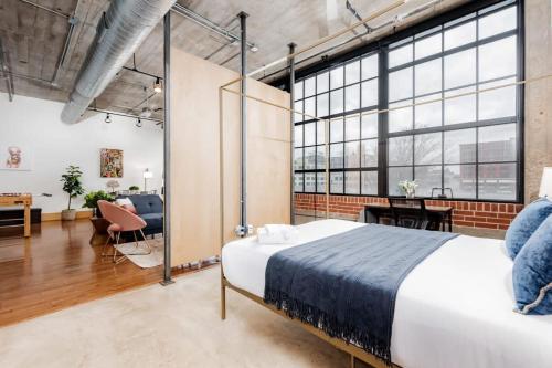 a bedroom with a large bed and a living room at TWO Astonishing Adler Loft by CozySuites in Saint Louis
