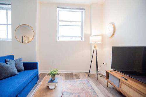 a living room with a blue couch and a flat screen tv at CozySuites The Block - Direct Skybridge Access #1 in Indianapolis
