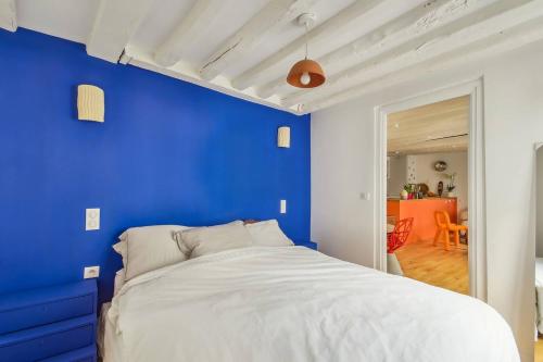 - une chambre bleue avec un lit et un mur bleu dans l'établissement Charming marais flat, à Paris