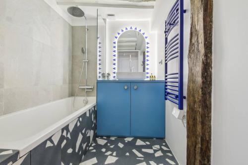 La salle de bains est pourvue d'une armoire bleue et d'une baignoire. dans l'établissement Charming marais flat, à Paris