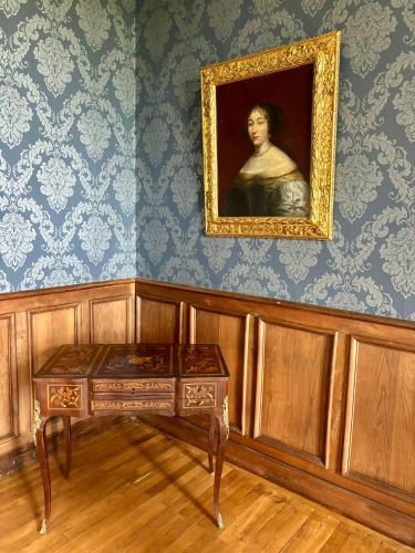 une peinture d'un homme dans une pièce avec une table dans l'établissement Château de la Pervenchère gîte Baroque, à Casson