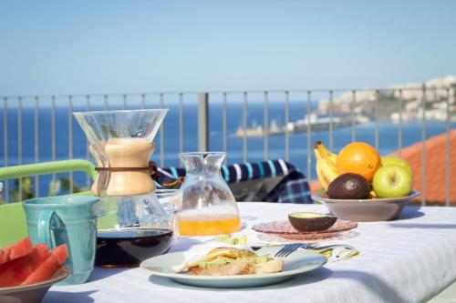 a table with a plate of food and a jug of juice at Irlandas Villa Funchal Seaside Villas in Funchal