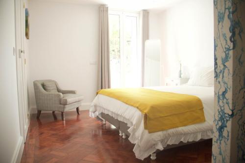 a bedroom with a bed and a chair and a window at Irlandas Villa Funchal Seaside Villas in Funchal