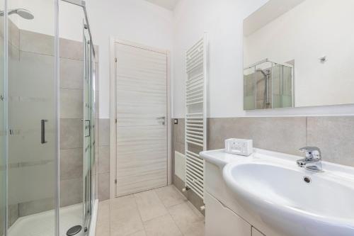 ein weißes Bad mit einem Waschbecken und einer Dusche in der Unterkunft Al Porto balcony close to the lake in San Felice del Benaco