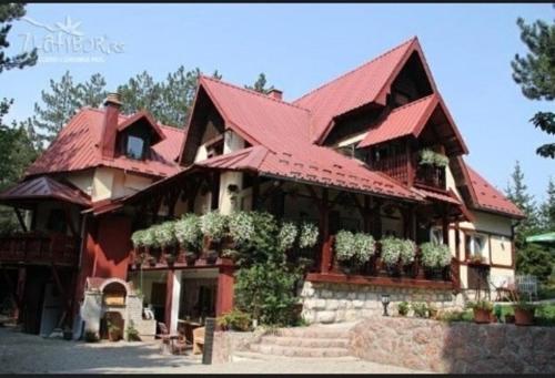 a large house with a red roof with flowers on it at Vila Miris borova Zlatibor CENTAR in Zlatibor