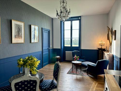- un salon avec des murs bleus, une table et des chaises dans l'établissement Château de la Pervenchère gîte Baroque, à Casson