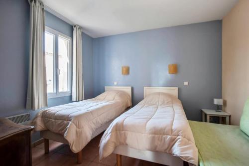 - 2 lits dans une chambre aux murs bleus dans l'établissement Village Pont Royal en Provence - maeva Home - Appartement 4 pièces 7 personnes, à Mallemort