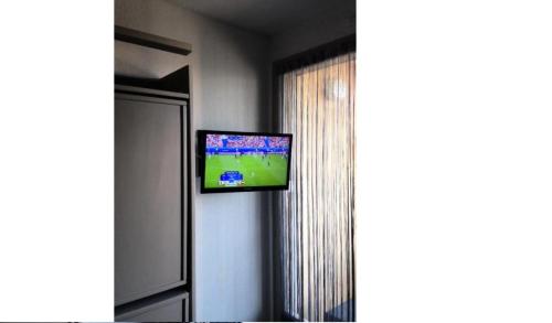 Une télévision à écran plat est installée sur un mur à côté d'une fenêtre. dans l'établissement Studio 2 personnes plages et criques - Studio 2 personnes MAE-9614, à Bormes-les-Mimosas