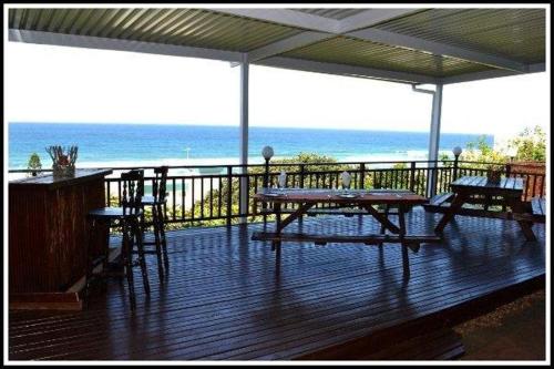 a deck with a table and chairs and the ocean at Bayview Guest House in Amanzimtoti