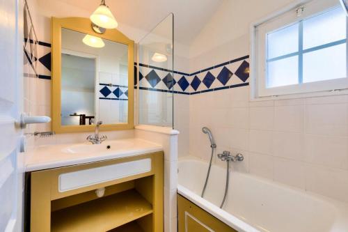 une salle de bain avec un lavabo, une baignoire et un miroir dans l'établissement Les Maisons de Port Bourgenay - maeva Home - Maison 3 Pièces 6 personnes Confort MAE-0320, à Talmont-Saint-Hilaire