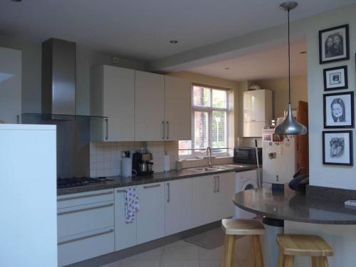 a kitchen with white cabinets and a table with stools at Home from Home 