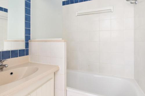 une salle de bain blanche avec une baignoire et un lavabo dans l'établissement Résidence Bleu Marine - maeva Home - Appartement 2 pièces 4 personnes Confort MAE-0708, à Lacanau