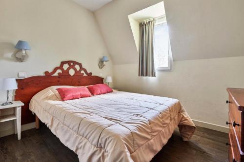 une chambre avec un grand lit avec deux oreillers rouges dans l'établissement La Résidence du Golf - maeva Home - Appartement 2 pièces 4 personnes Selection MAE-1110, à Deauville