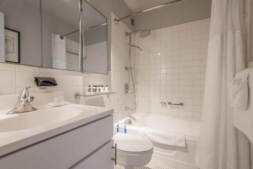 a bathroom with a sink and a toilet and a tub at TWO 800 Tower CozySuites w skypool lounge 8FL in Louisville
