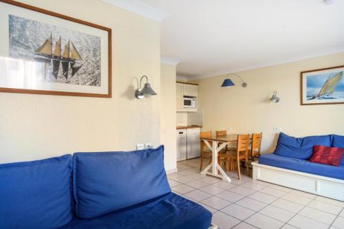 un salon avec un canapé bleu et une cuisine dans l'établissement Résidence Bleu Marine - maeva Home - Studio 3 personnes Confort MAE-0709, à Lacanau