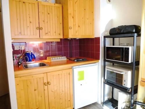 a small kitchen with wooden cabinets and a microwave at Résidence Lienz - Appartement avec terrasse exposé Sud, proche du centre de Barèges MAE-8454 in Barèges
