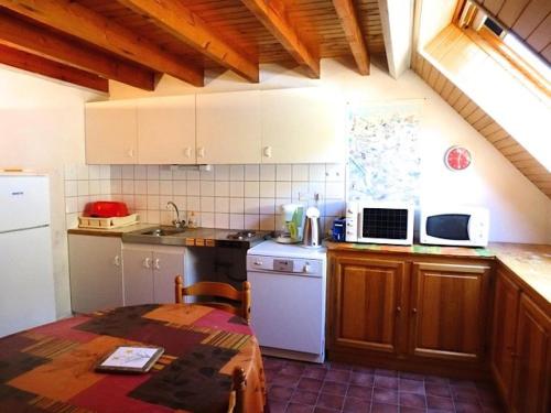 une cuisine avec une table et un réfrigérateur blanc dans l'établissement Résidence Casino - Appartement mansardé, 6 couchages avec mezzanine proche du centre de Barèges MAE-8464, à Barèges